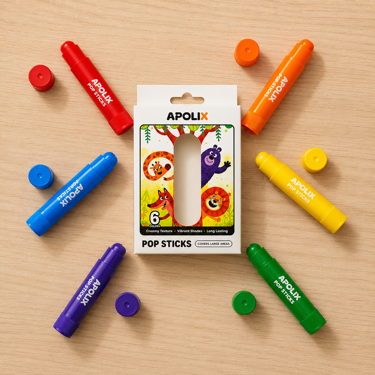 A boxed set of colorful APOLIX Pop Sticks crayons arranged on a light wood surface, with the package centered and several crayons in red, orange, blue, yellow, green, and purple placed around it.