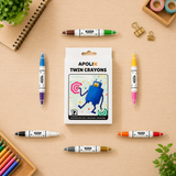 A set of 12 APOLIX twin crayon markers arranged on a light wood desk with school supplies. The center shows the white product box with a blue robot illustration, surrounded by the individual markers in various colors including blue, purple, brown, yellow, pink, orange, gray, and gold.